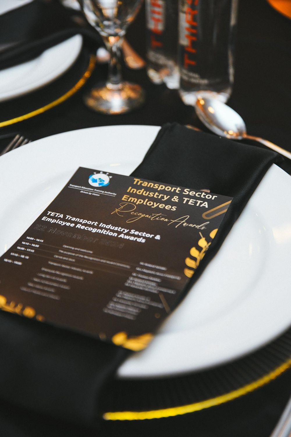 Black and gold awards programme card on a dinner plate