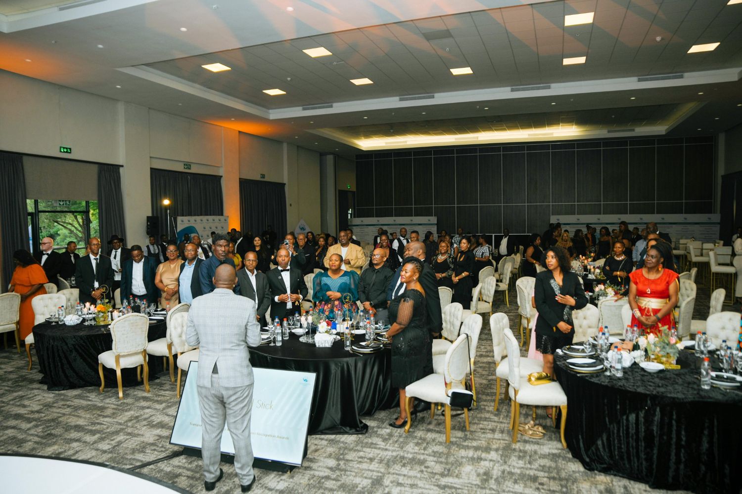 Guests standing at their tables during a speaker's session