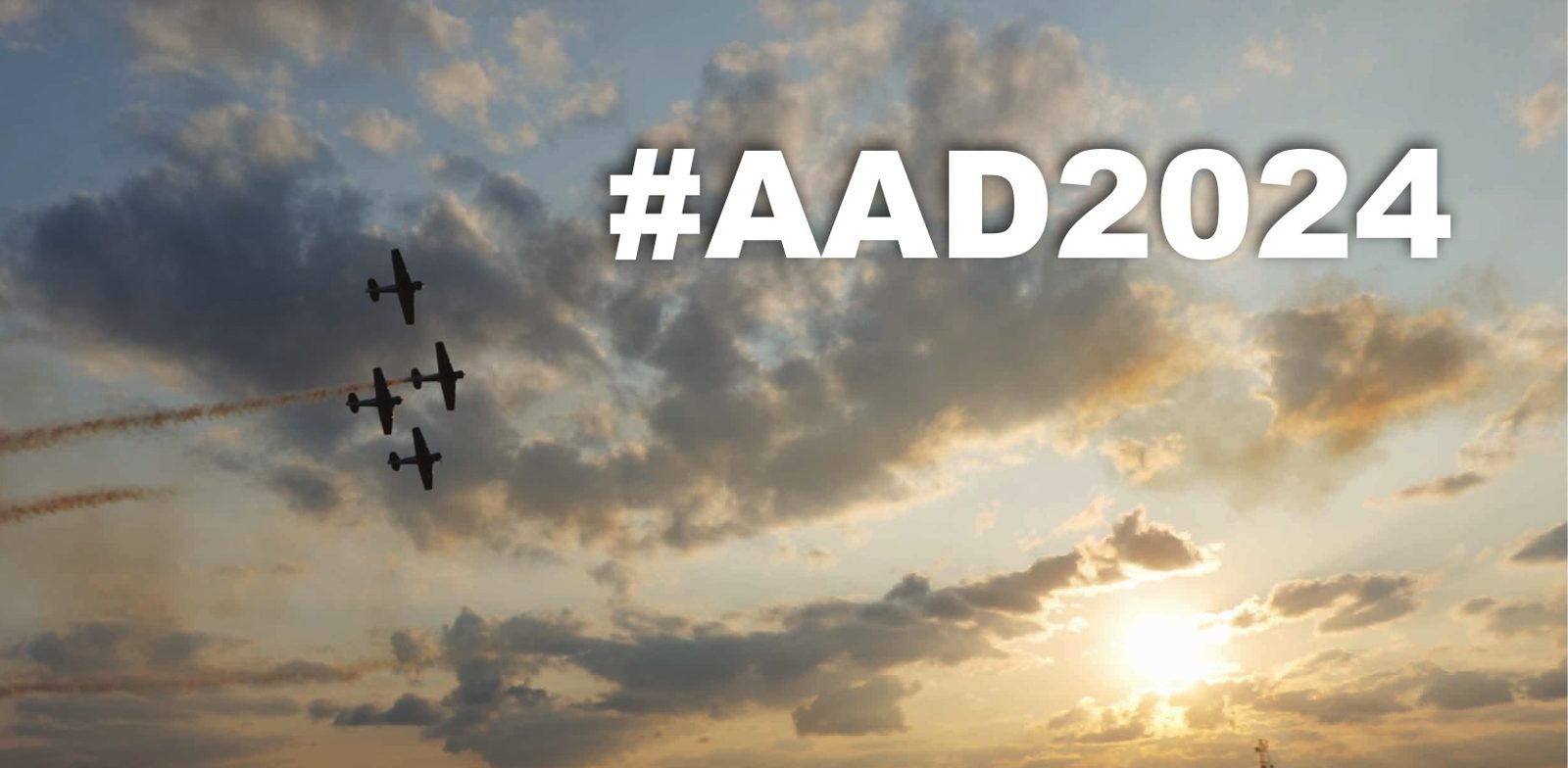 Aerobatic aircraft trailing smoke across a sunset sky