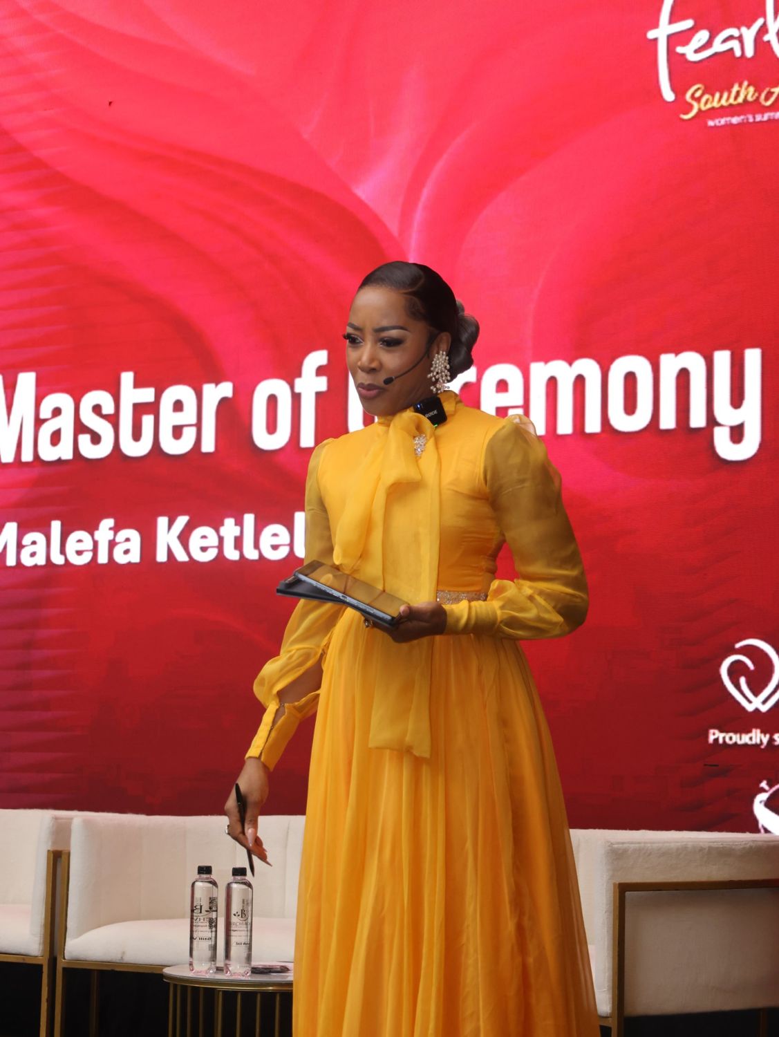 Master of Ceremonies in a yellow gown on stage
